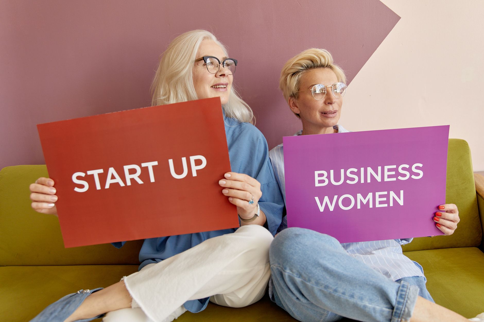 Two women on a sofa holding signs promoting startup and business women. — 5 Ways To Make Your Retail Space More Environmental
