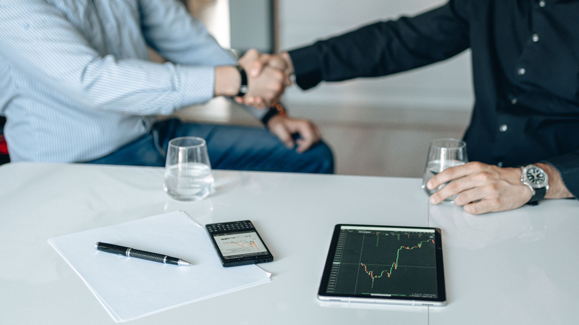 Business meeting with handshake and financial analysis displayed on a tablet. — Avail Comprehensive Car Insurance Policy In H