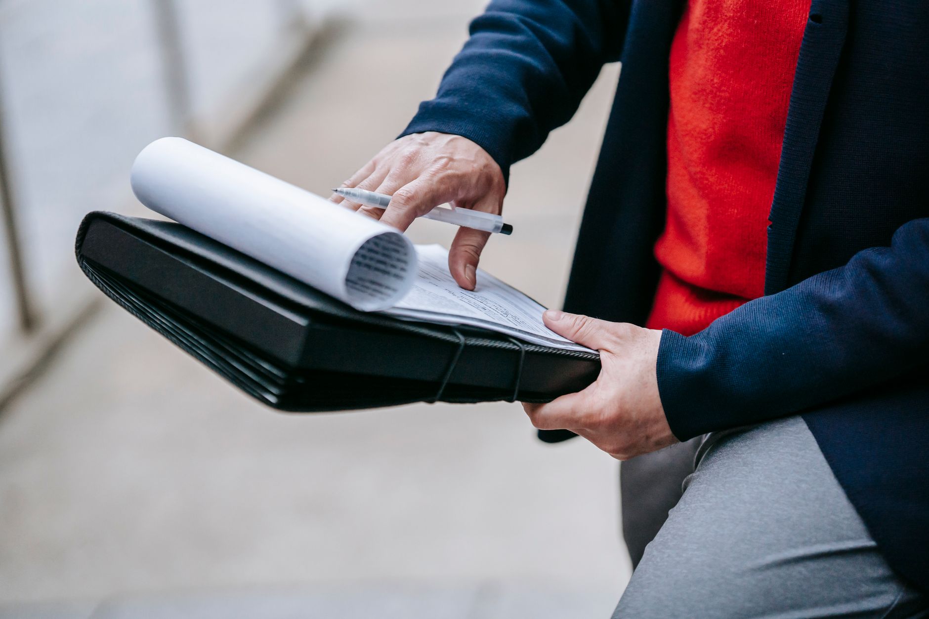 Close-up of a professional person reviewing documents outdoors. Engaged in work with focus on writing materials. — Explore Ho
