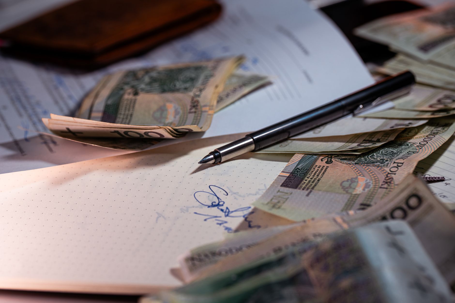Overhead view of Polish banknotes, documents, and a pen on a desk — Find clear steps to apply for financial assistance on Ped