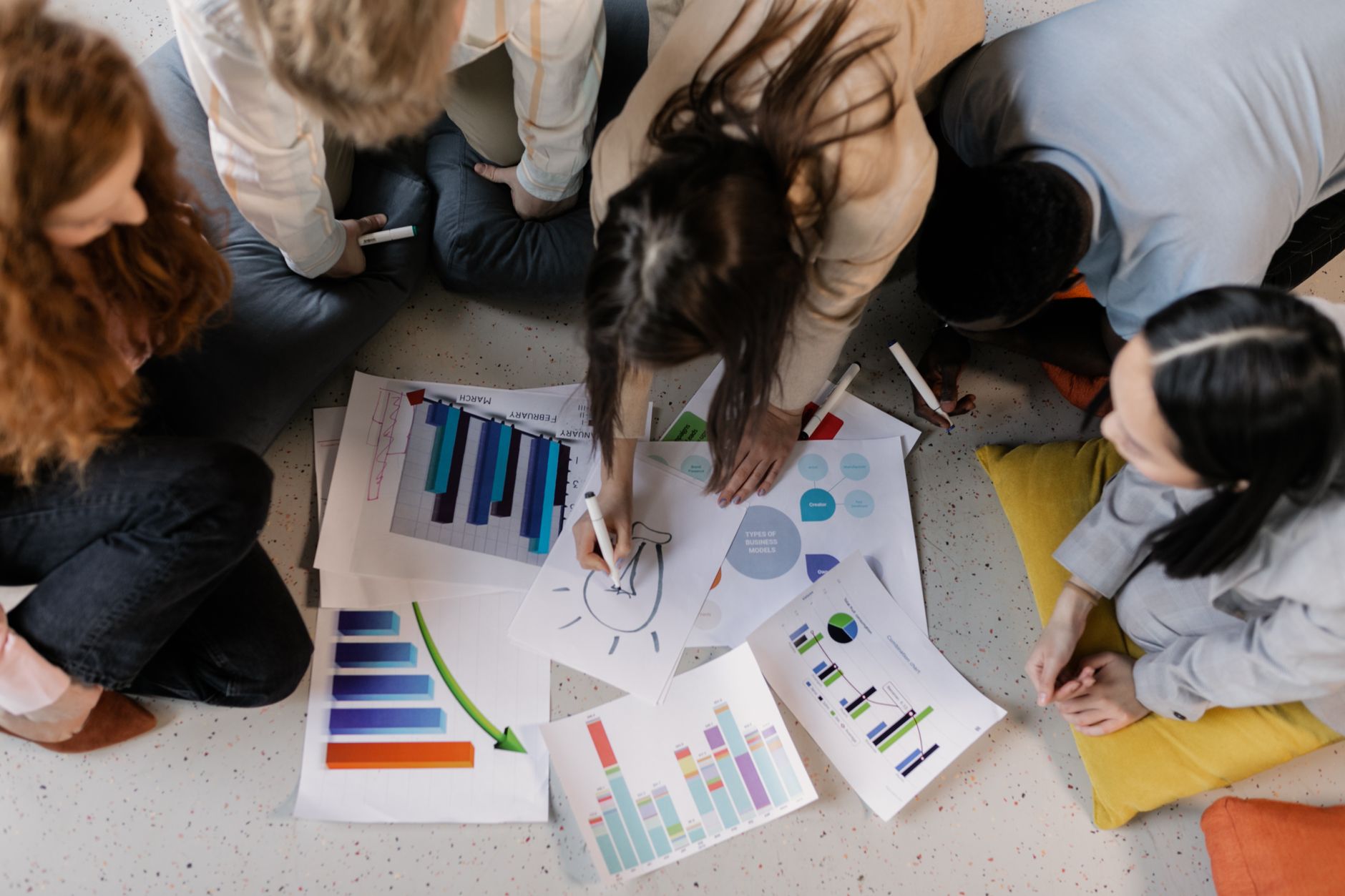 Overhead view of diverse team brainstorming on business strategy using charts and graphs. — International SEO Beyond Translat