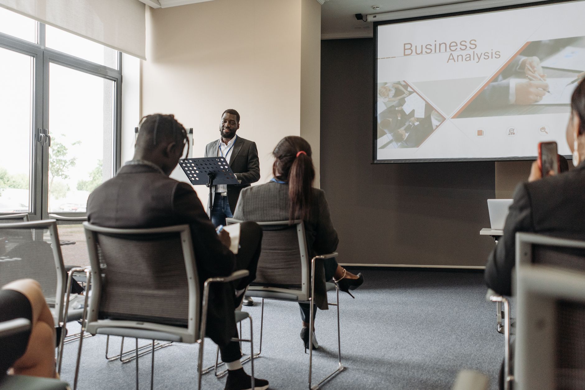 A business professional delivering a presentation in a conference room with diverse attendees. — Maintain Exchange Reputation