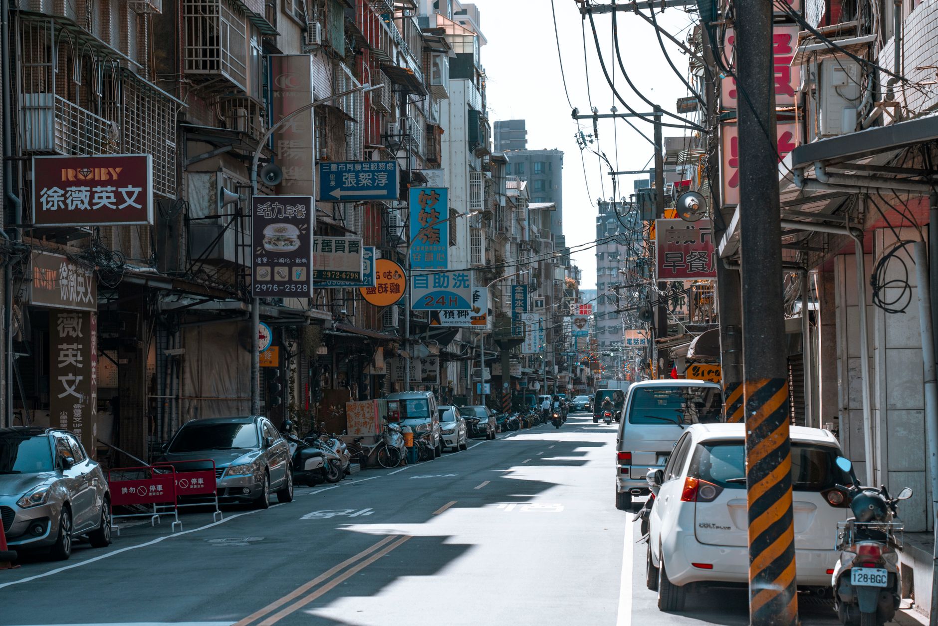 A busy street lined with cars and various colorful business signs on a sunny day. — Movie Theater Usher