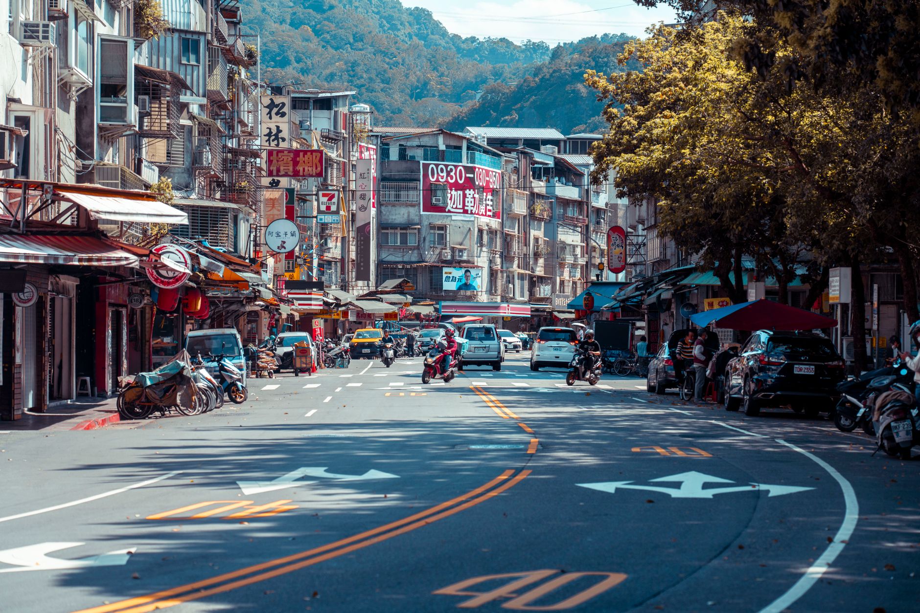 Vibrant urban street scene with shops, vehicles, and mountains in an Asian city. — What makes CFD a lucrative investment stra